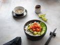 Poke bowl served with salmon, avocado, cucumber and rice on a gray background. Buddha bowl