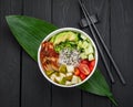 Poke bowl with smoked eel, rice, avocado, cucumber, cream cheese, tomato and pear on dark background Royalty Free Stock Photo