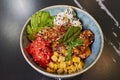 A poke bowl with tuna, avocado slices, wasabi, corn, peanut, sesame, cheese