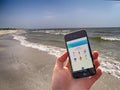 Pokemon Go game in hand held smartphone on beach summer background