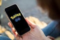 woman sitting in the street holding her smartphone with pokemon