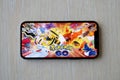 Pokemon GO mobile iOS game on iPhone 15 smartphone screen on wooden table during mobile gameplay