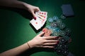 Poker cards and chips in hand on green background