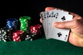 Poker cards with flush combination. Close-up of a gambler hand is holding playing cards in casino. Chips on the green table Royalty Free Stock Photo