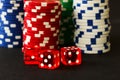 Poker Chips with Red Dice in forground on black backgrund with reflections Royalty Free Stock Photo