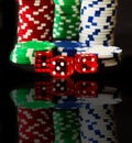 Poker Chips with Red Dice in forground on black backgrund with reflections Royalty Free Stock Photo