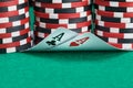 Poker chips stand as background for two playing cards lying on a green table Royalty Free Stock Photo