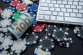 Poker chips and wads of dollars on a laptop keyboard scattered over a plain background. Royalty Free Stock Photo