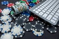 Poker chips and wads of dollars on a laptop keyboard scattered over a plain background. Royalty Free Stock Photo