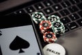 Poker play online concept. Poker chips, playing cards and smartphone on keyboard Royalty Free Stock Photo