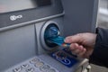 a retired woman near an ATM holds a master card bank card in her hands to withdraw money