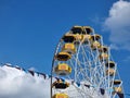 Poland, Rabka Zdroj, Rabkoland amusement park, funfair, Ferris wheel with open gondolas, blue cloudy sky. Fairground symbol