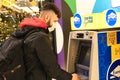 POLAND, TORUN - December 5, 2020: Man withdraws cash near ATM. Person in casual style wearing protective mask on his face in mall