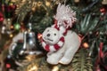 Polar bear Christmas ornament with red & white scarf and crooked nose and funny expression against bokeh decorated tree withh ligh