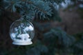Polar bear snow globe ornament hanging in a tree with copy space