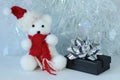 Polar bear wearing a hat and a red scarf posed next to gifts with shiny knots on a Christmas holiday decor Royalty Free Stock Photo