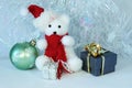 Polar bear wearing a hat and a red scarf posed next to gifts with shiny knots on a Christmas holiday decor