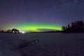 Polar northen lights aurora borealis at night in the starry sky above the lake with the island and the silhouette of the trees by Royalty Free Stock Photo