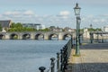 Pole lamps on the cobblestone sidewalk, the river Maas, the Servatius Bridge and the cityscape in the background