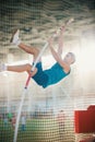 Pole vaulting indoors - young fit man jumping leaning on the pole - sport stadium Royalty Free Stock Photo