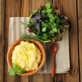 Polenta with basil shoot in wooden bowl with green salad bowl an