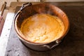 Polenta cooked in a copper cauldron on a wood stove