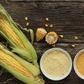 Polenta corn grits and corn flour in a porcelain bowl on a wooden table. Ears of corn and pieces of corn next to bowls. Gluten