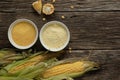 Polenta corn grits and corn flour in a porcelain bowl on a wooden table. Ears of corn and pieces of corn next to bowls. Gluten