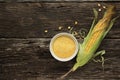 Polenta corn grits a porcelain bowl on a wooden table. Ears of corn and pieces of corn next to bowls. Gluten Free Healthy Eating