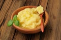 Polenta with green basil in wooden bowl with wooden spoon