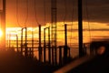 Poles at a power plant at sunset as a background Royalty Free Stock Photo