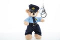 Cute teddy in policeman uniform and handcuffs isolated against white background