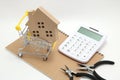 Police caMiniature house, shopping cart, calculator and tools on white back and ambulance heading to hospital on white background.