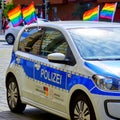 Police car decorated with flags in the colors of the rainbow, on the edge of a march for CSD Christopher Street day