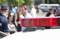 Police car flashing light in focus, blurred people in background