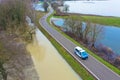 A police car patrols an asphalt country road during floods. Flood disaster in winter.
