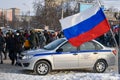 Police car and the Russian flag against background of crowd of people moving along road. Action in support of Alexei Navalny.