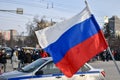 Police car and the Russian flag against background of crowd of people moving along road. Action in support of Alexei Navalny.