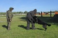 Police dog attacking a suspect man wearing protective cloth, a dog handler watching, training. Novo-Petrivtsi military