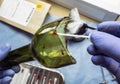 Police expert gets blood sample from a broken glass bottle in Criminalistic Lab