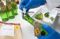 Police expert gets blood sample from a green glass bottle in Criminalistic Lab