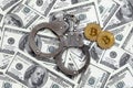 Police handcuffs and bitcoins lie on a large number of dollar bills. The concept of problems with the law during the illegal cryp Royalty Free Stock Photo