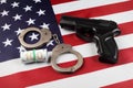 Police handcuffs dollars and a gun on the USA flag close-up
