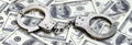 Police handcuffs lie on a lot of dollar bills. The concept of illegal possession of money, illegal transactions with US dollars. Royalty Free Stock Photo