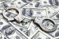 Police handcuffs lie on a lot of dollar bills. The concept of illegal possession of money, illegal transactions with US dollars. Royalty Free Stock Photo