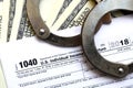 Police handcuffs lie on the tax form 1040. The concept of proble