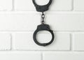 Police handcuffs on a white painted brick wall