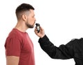 Police inspector conducting alcohol breathe testing, man blowing into breathalyzer on white background Royalty Free Stock Photo
