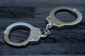 Police metal handcuffs on dark wooden background.