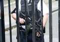 Police officer in a defensive position, equipped with a sidearm, in front of a chain-link fence